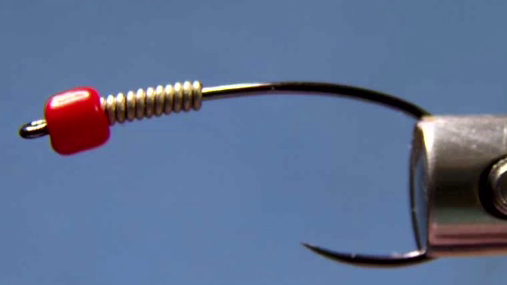 Slide on a misshaped red glass bead and add 10 wraps of .020 lead-free wire behind it.