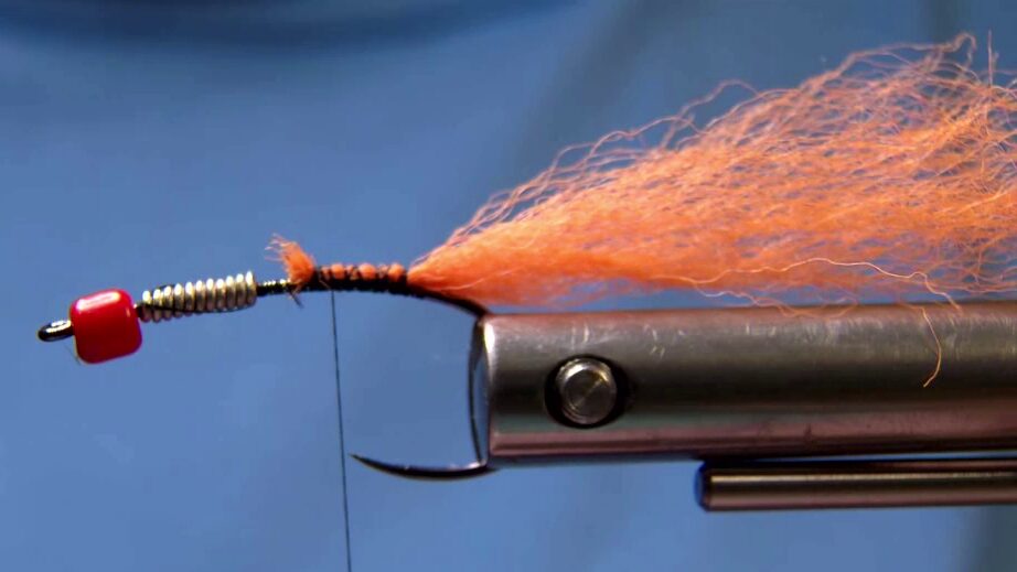 Start black 14/0 thread and cover the hook shank. Tie in an uneven orange poly yarn tail at the bend.