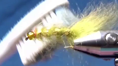 A small red thread collar is wrapped neatly behind the bead. The finished fly shows a brushed, full-bodied olive profile with gold ribbing and a green bead head.