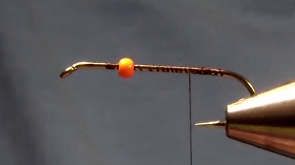 Hook in vise with bright orange bead at the eye, thread wrapped evenly down the shank to the bend.