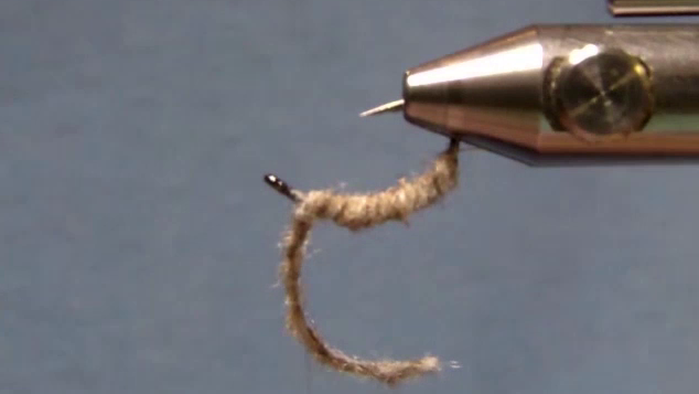 Segmented poly yarn body wrapped to hook eye with long cord tag left out front.